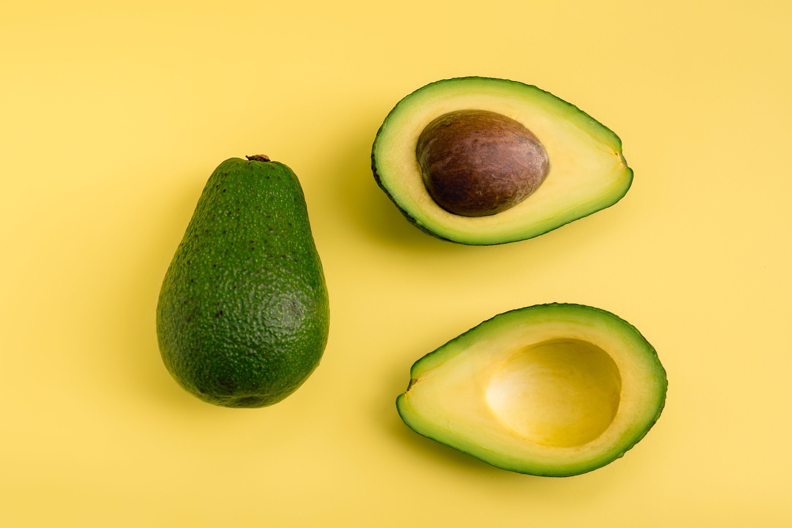 Avocado flat lay on yellow background. Simple and minimal concept. Organic healthy food. Top view