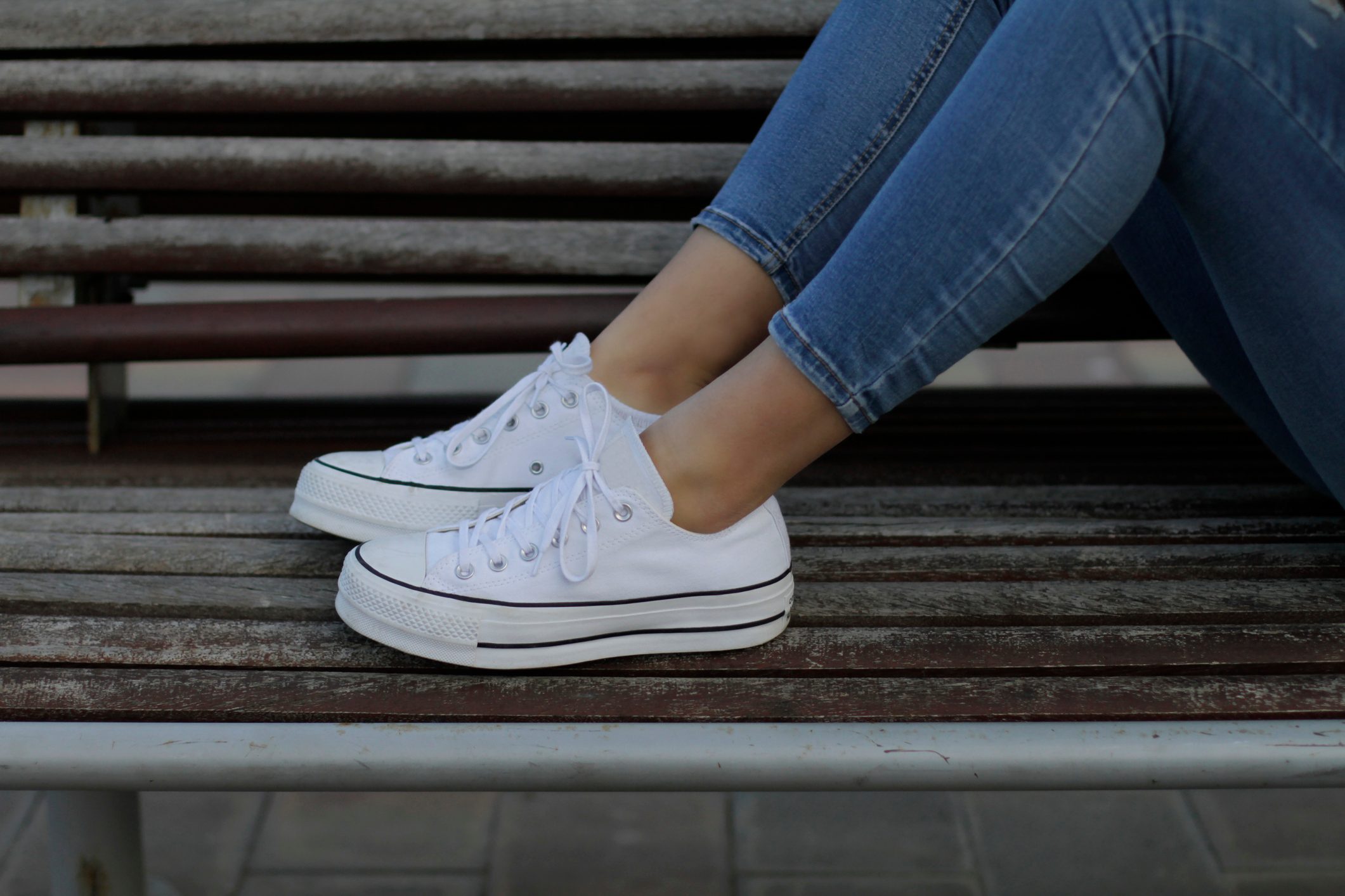 Young woman with sneakers on bench