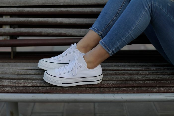 Young woman with sneakers on bench