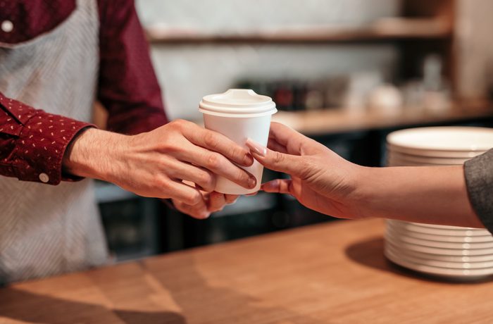 Crop barista giving beverage to client