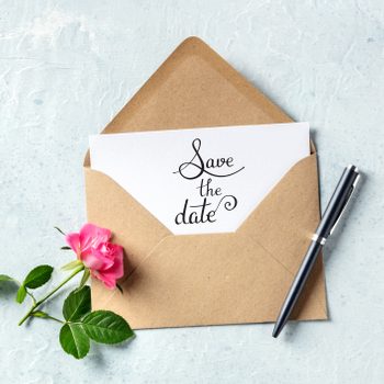 Save the date lettering on an invitation in a brown kraft envelope, shot from above