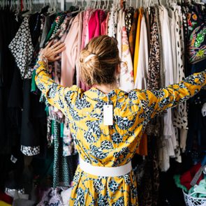 Fashionable woman in yellow dress choosing from clothes rack