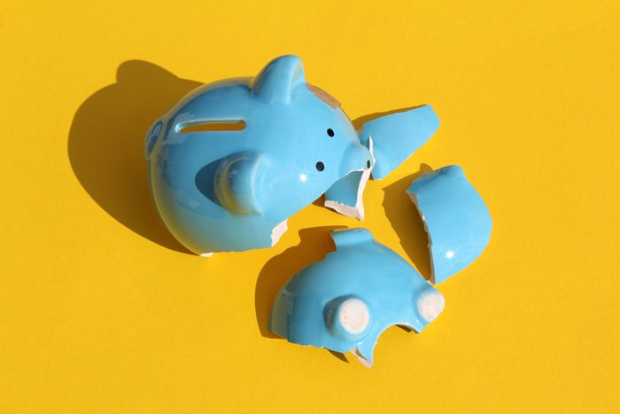 On a yellow background lies a broken blue piggy bank.