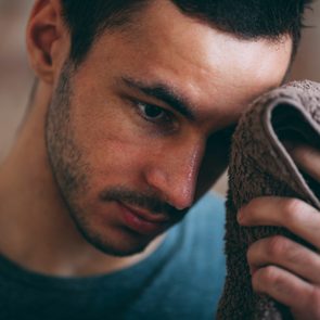 man wiping sweat off of forehead with a towel in undisclosed location