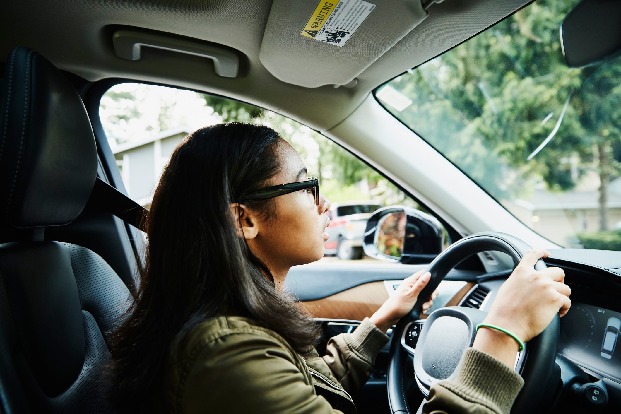 Young woman sitting in drivers seat of car waiting for driving lesson