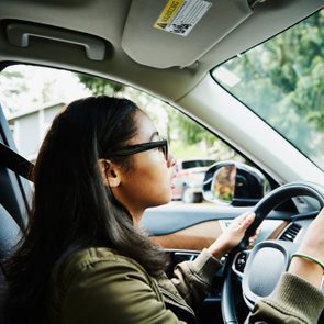 Young woman sitting in drivers seat of car waiting for driving lesson