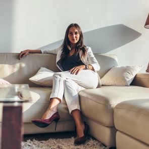 Portrait of a woman sitting on sofa relaxing after work at home, dressed in the quiet luxury aesthetic