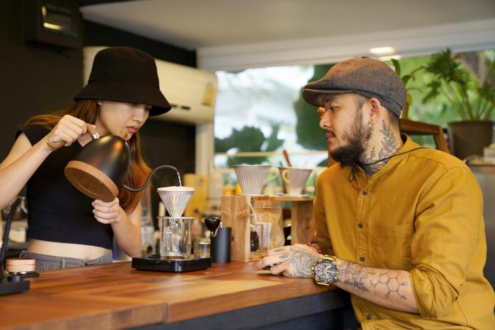 Barista woman brewing coffee serving client at coffee bar