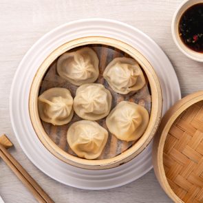 Steamed pork soup dumplings i na steamer with a spoon, chop sticks, dipping sauce