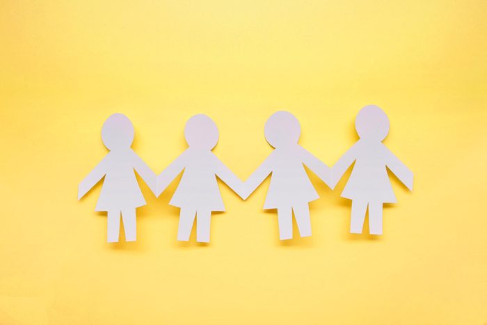 Paper Figures Hold Hands on a yellow background