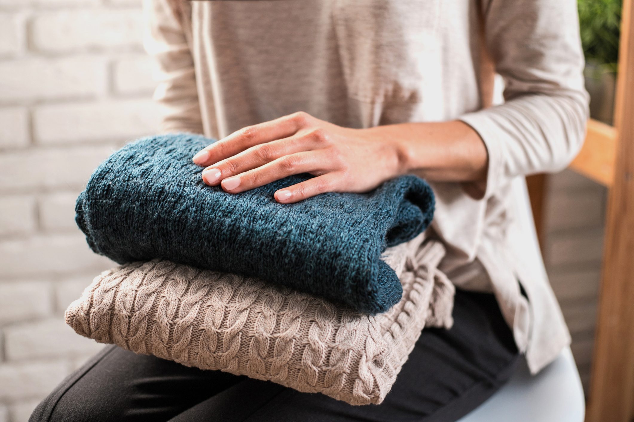 Woman's hands holding knitted clothes. Close up.
