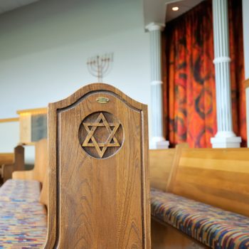 interior of a jewish temple with a star of david carved in the wood at the end of the bench