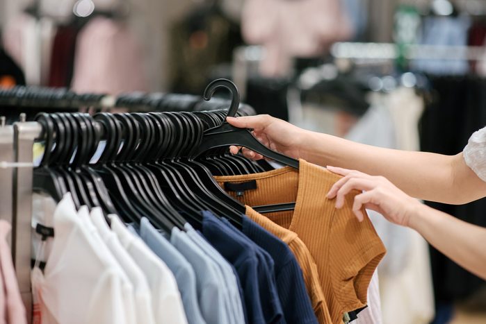 Close-up of asian chinese female hand taking a clothes out at clothing store