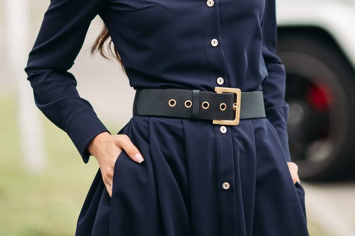 Beautiful woman in dark blue dress with hands in pockets.