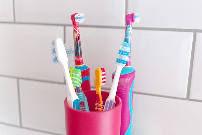A variety of toothbrushes, including electric toothbrushes in a bathroom setting