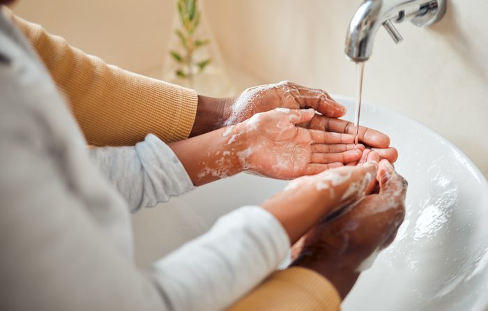 People cleaning hands, soap and skincare with hygiene in bathroom, self care with skin and water for wash. Parent helping child, clean with quality time together and family home, health and wellness