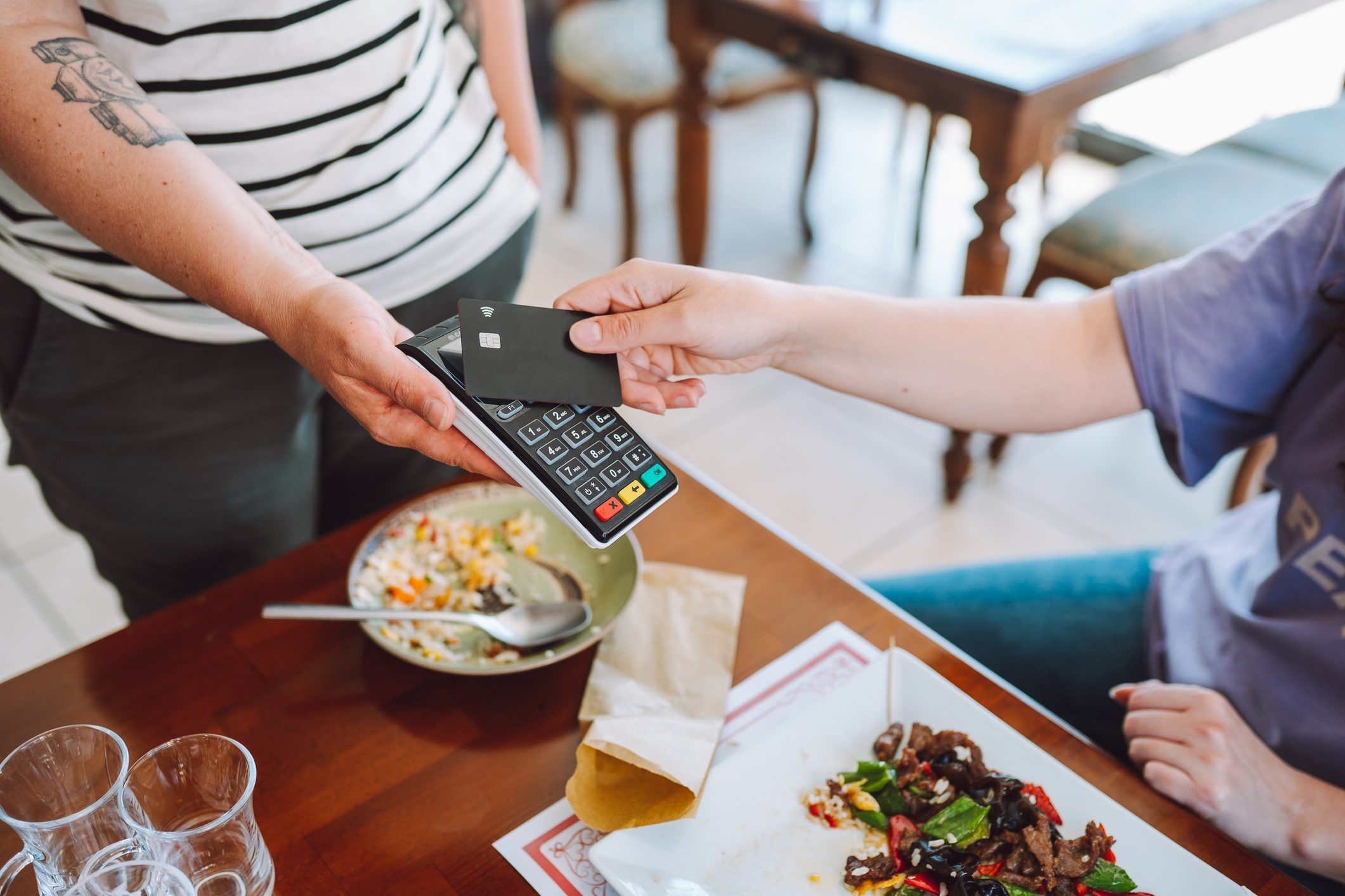 Contactless payment in restaurant. Wireless card reader scanning credit card from customer hand in cafe, high angle view