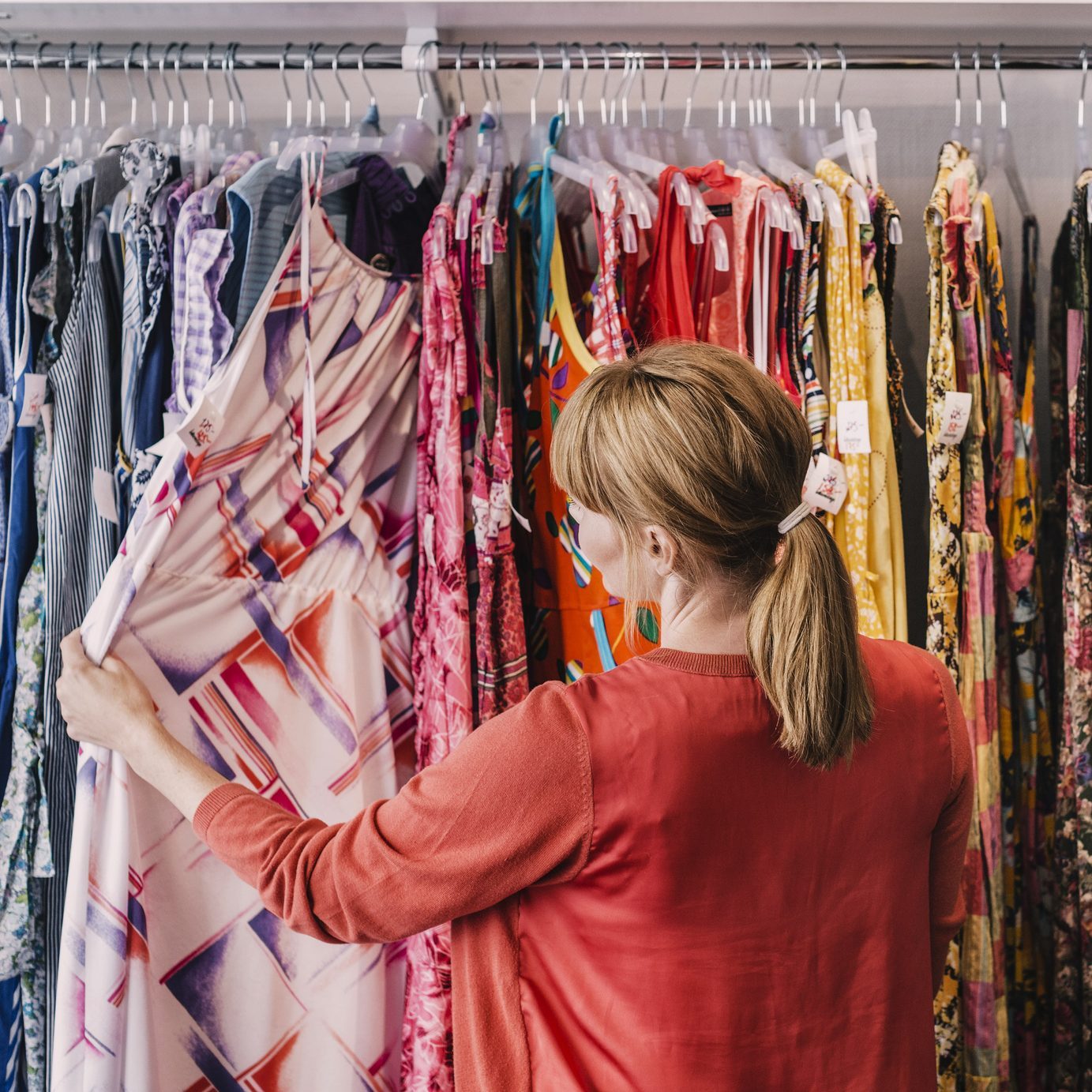 Woman looking at dress hanging on rack while standing at store