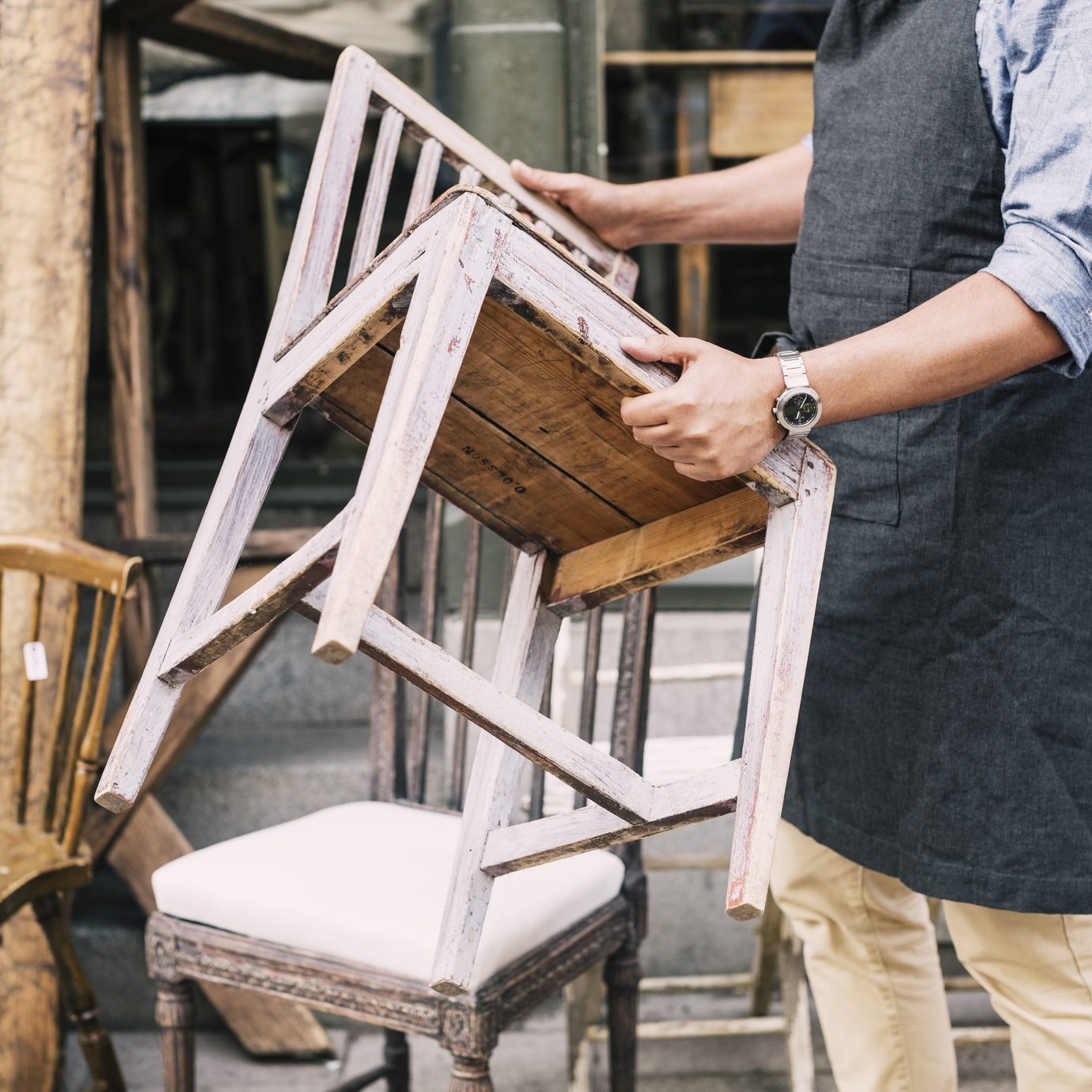 Midsection of man holding chair while standing against store