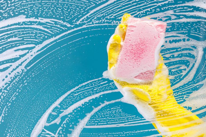 hand cleaning glass window pane with detergent and wipe or sponge