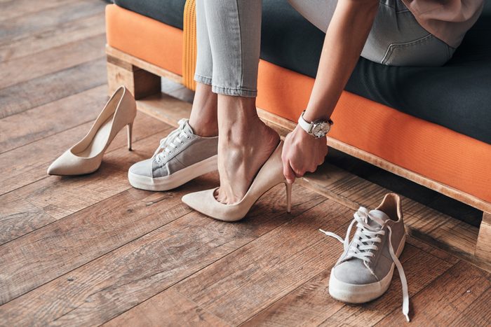 Close up of young woman trying on elegant shoes with high heels while sitting in the shoe store
