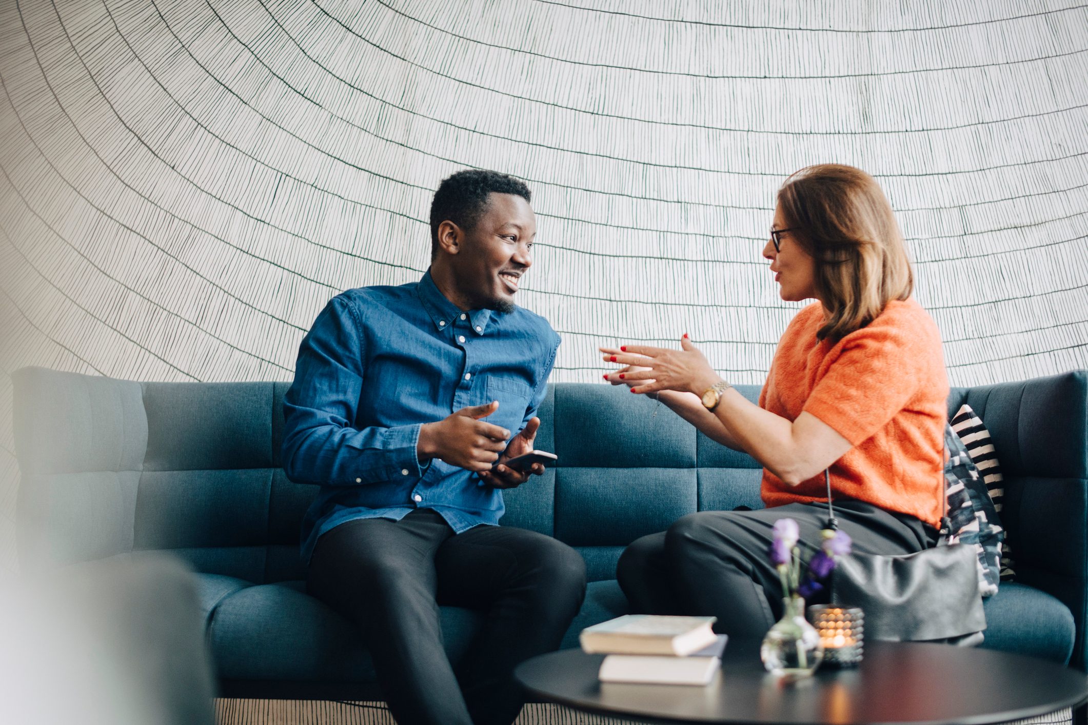 Businessman and woman sitting on couch during conference