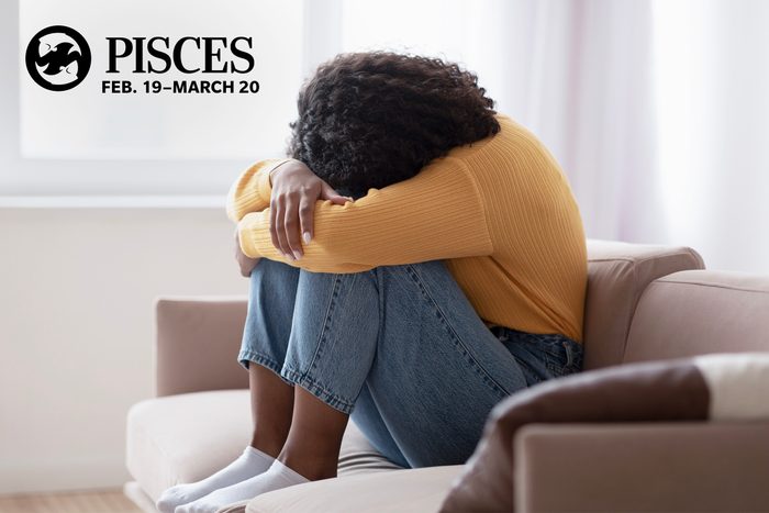 young woman with her head in her lap crying