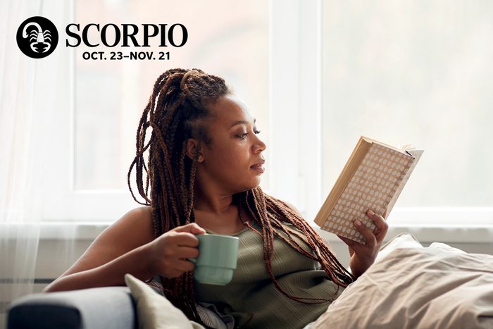 woman reading book and drinking tea on a couch