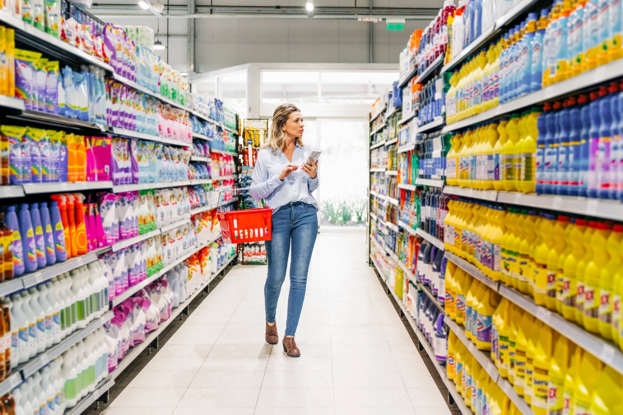 Woman Customer With Mobile Phone Buying Groceries In Store