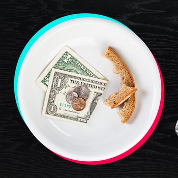 white plate with dollar bill, coins, and crust of bread on black wood background between and fork and knife. the plate has been given blue and pink edges similar to the tiktok logo
