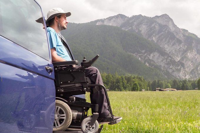 Man On Wheelchair Going Out Of A Car On Electric Lift Specialized Vehicle For People With Disabilities