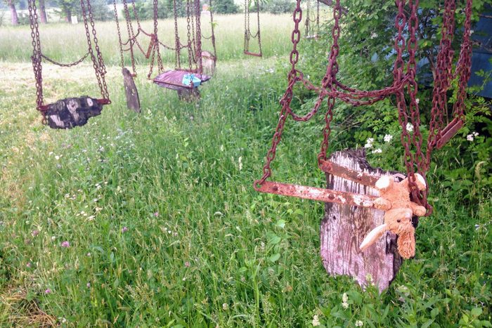 Stuffed rabbit hanging from old wooden swing