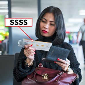 woman looking at a boarding pass at an airport with 