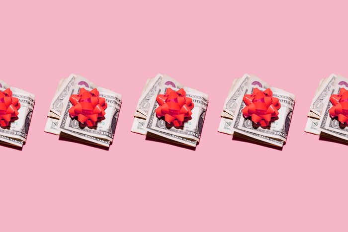 Studio shot of row of folded dollar bills with red gift bows