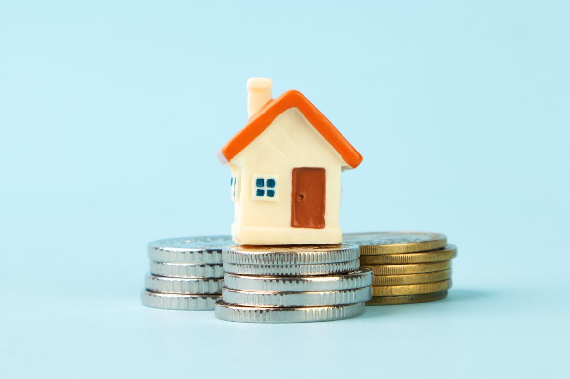 Miniature house standing on stacks of coins. The concept of real estate, mortgage, home insurance, home purchase and sale.