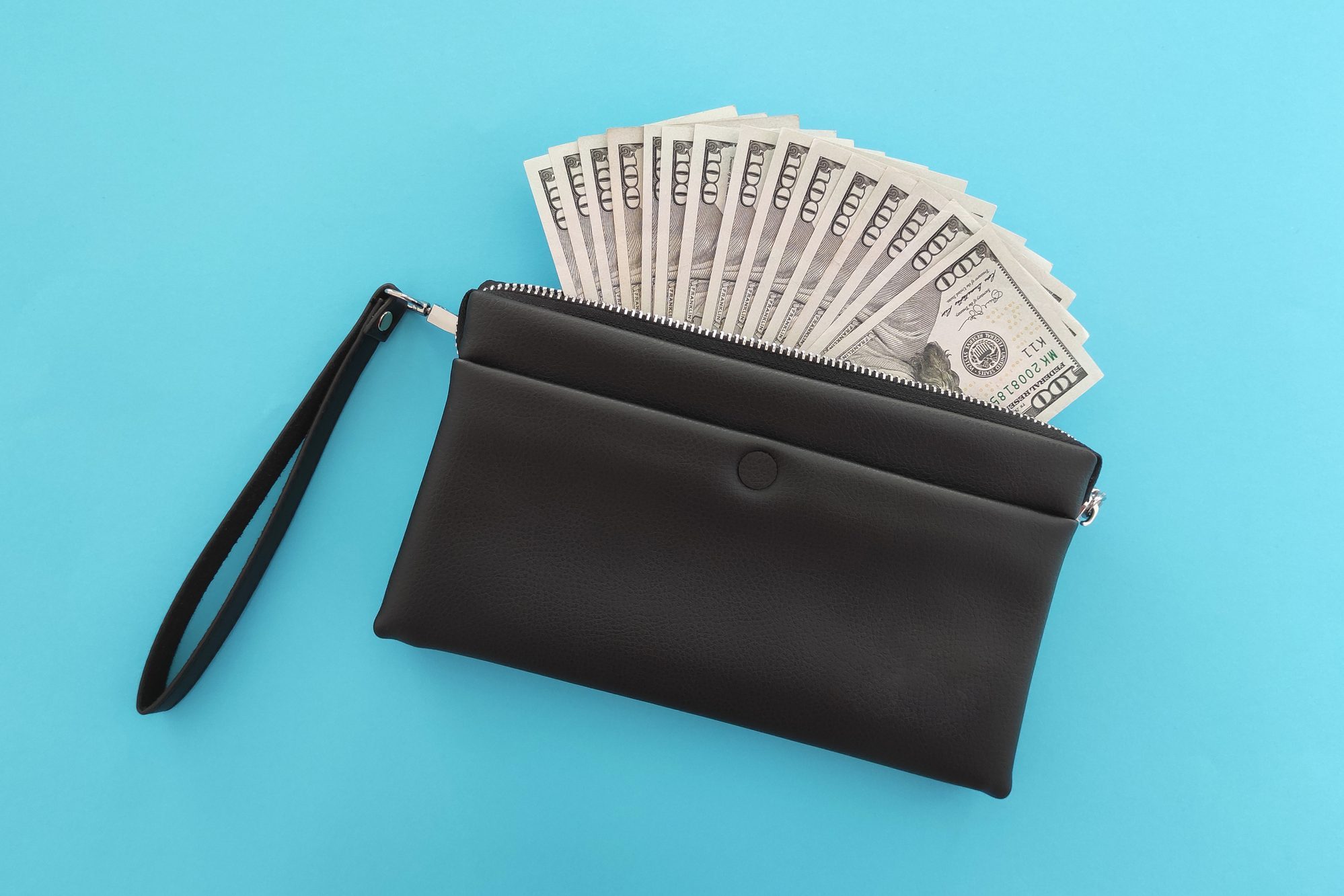 Dollar banknotes in black wallet on blue background