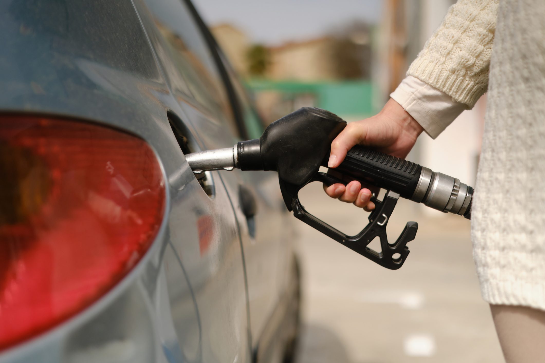 unrecognizable woman using gas pump to add fuel to her car during energy crisis