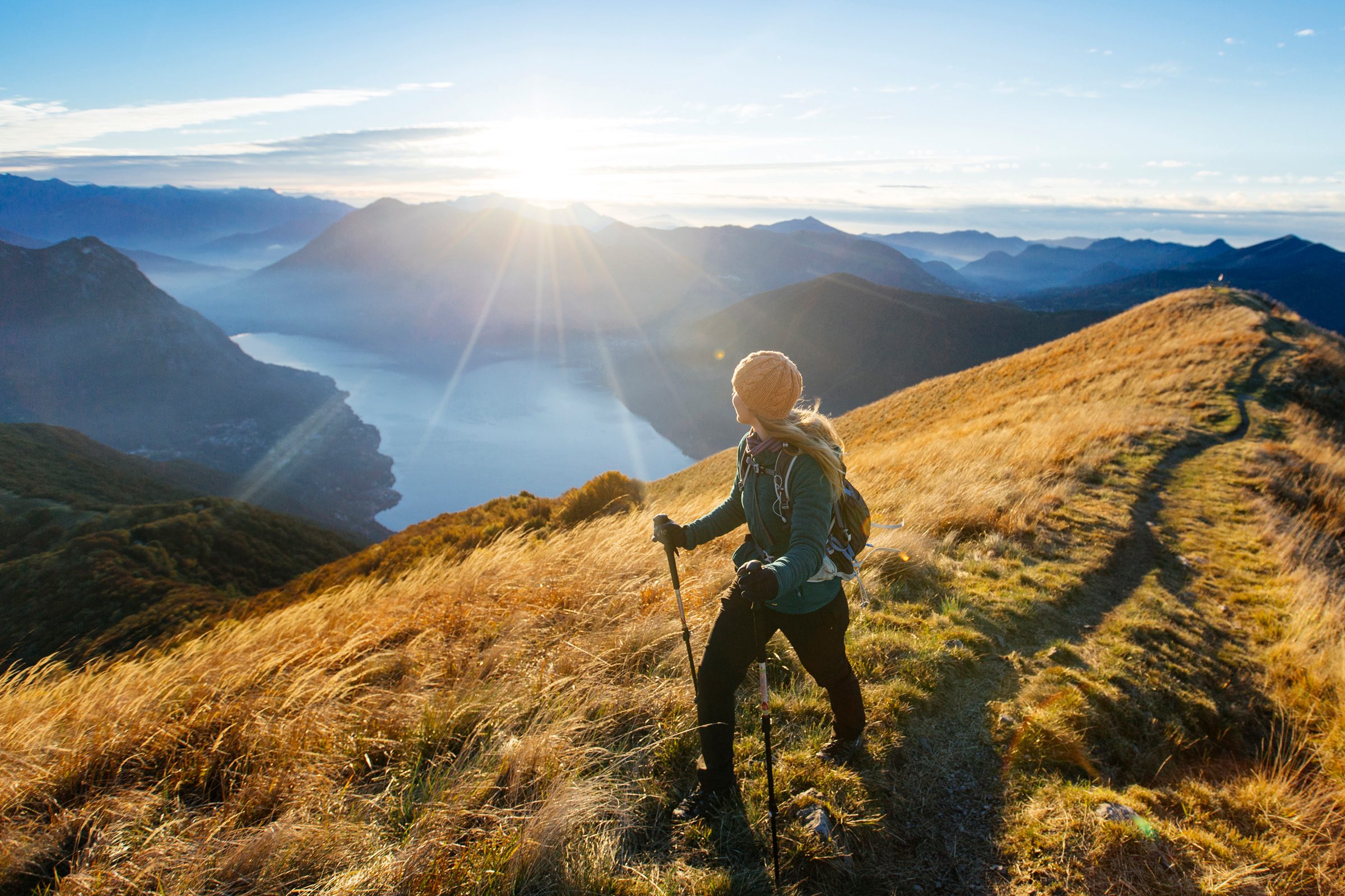 Woman hikes along ridgecrest above lake, valley