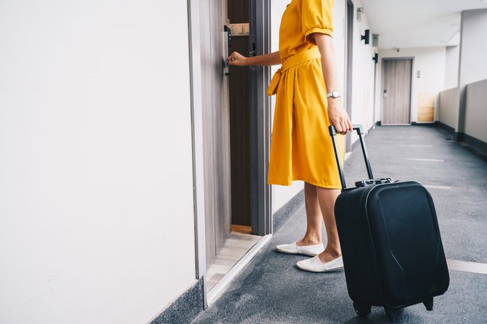 Cropped shot view of tourist woman pulling her luggage to her hotel room after check-in.