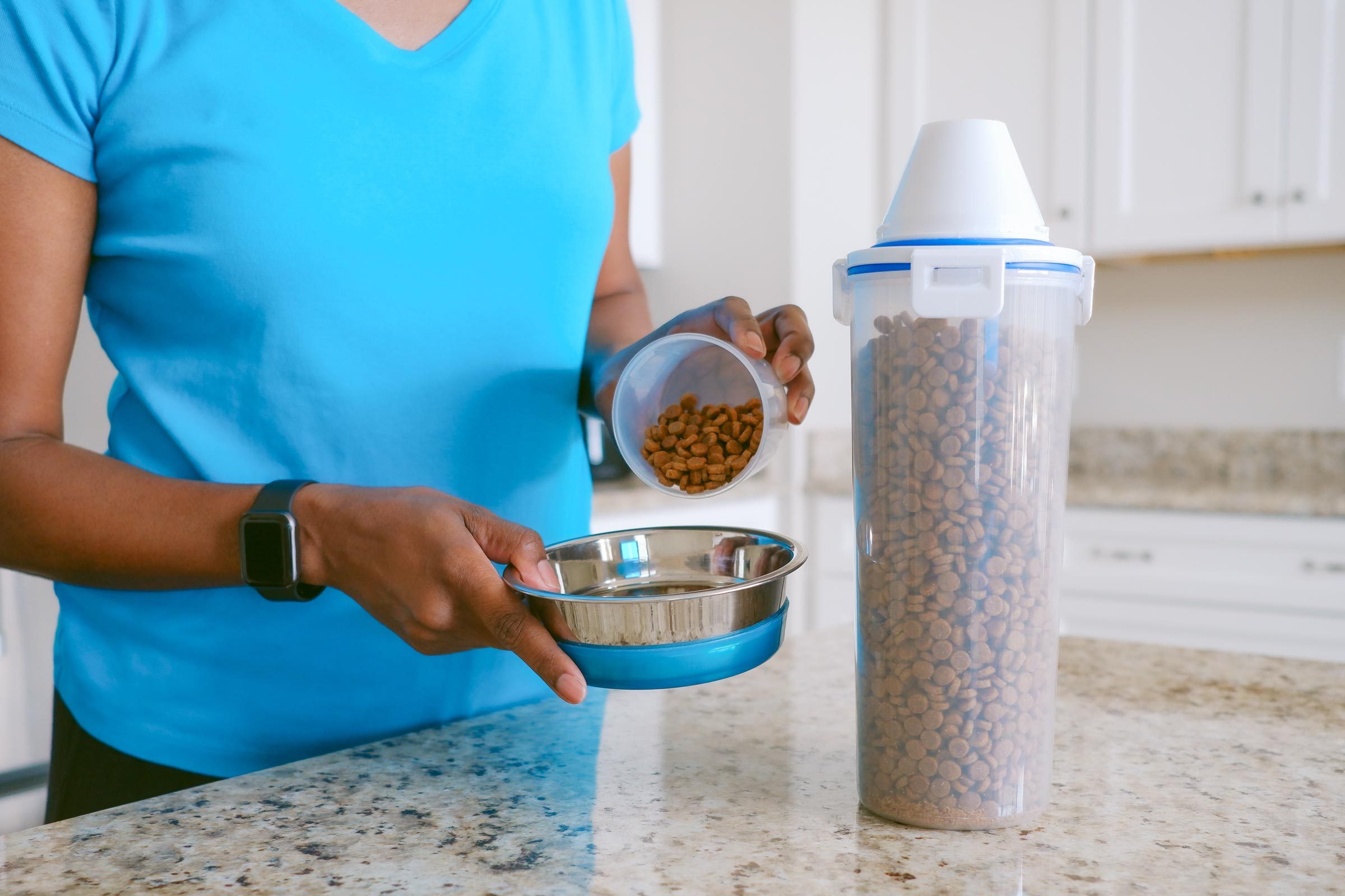 pouring cat food into a bowl on a kitchen counter