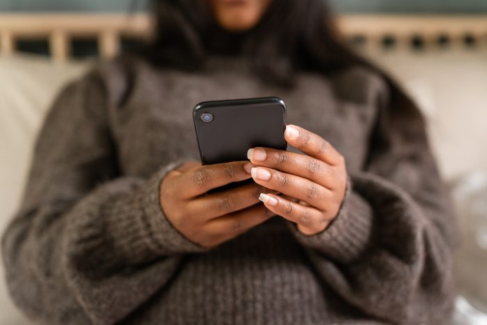 Woman using her smartphone in the bedroom