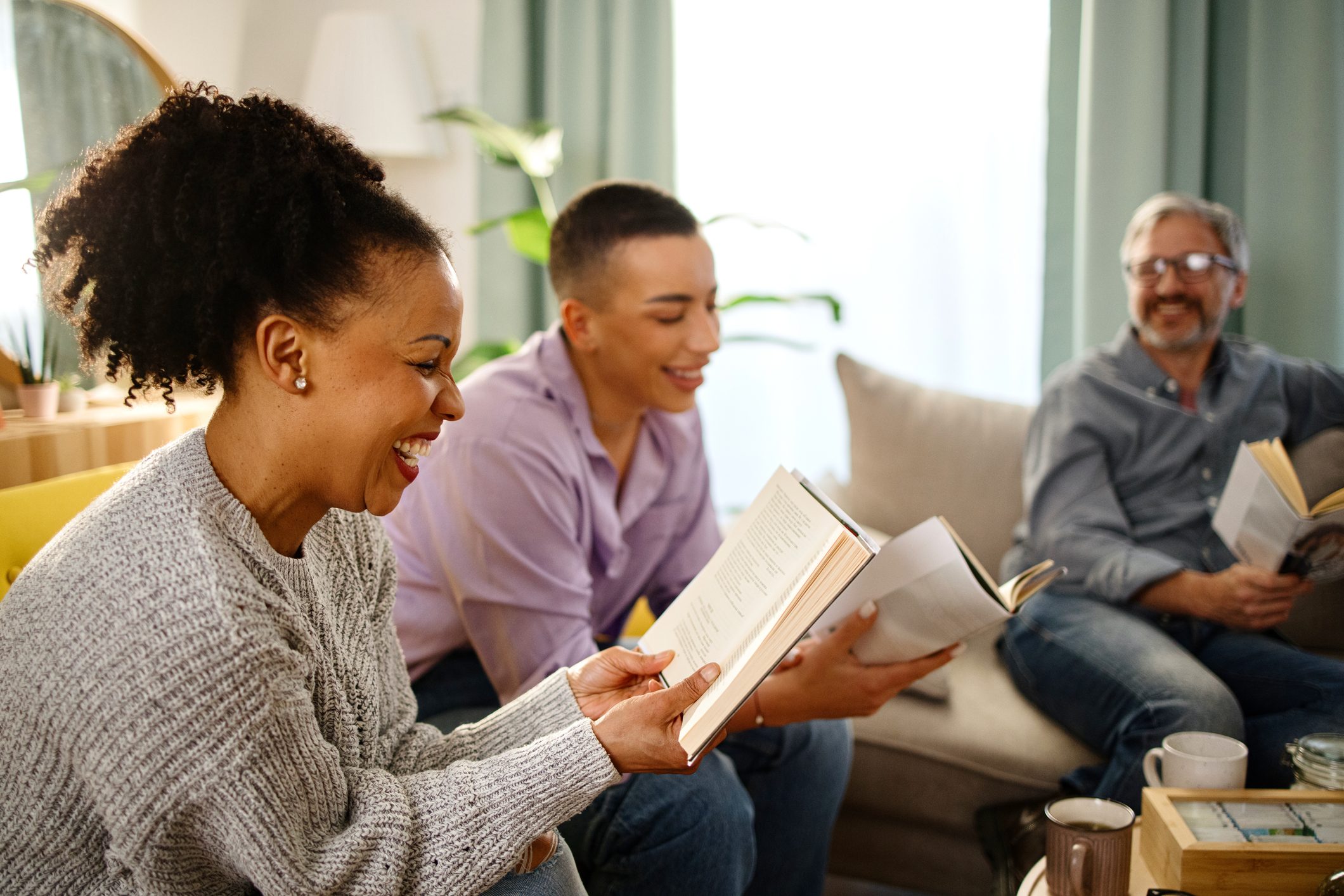 Group of people with a mixed age range talking and laughing while having a book club meeting.