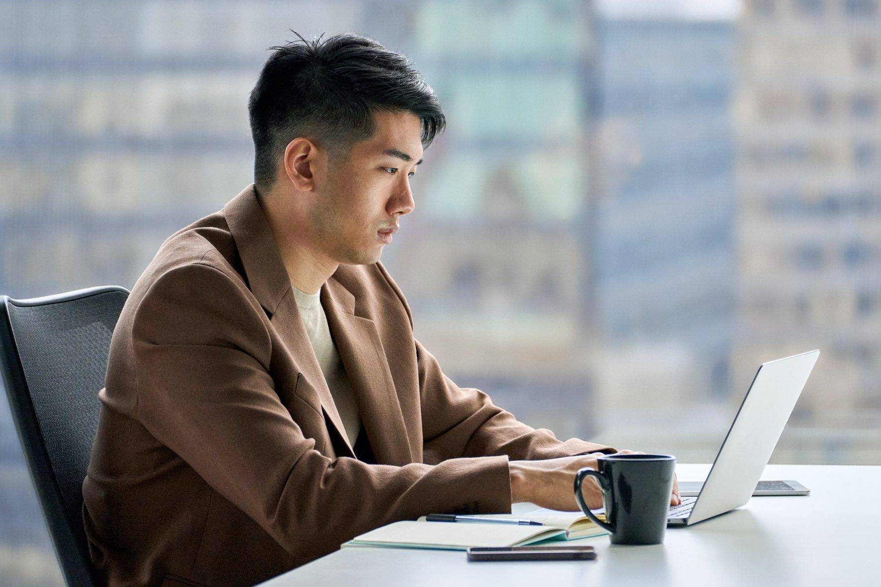 Busy professional Asian business man working typing on laptop in office.