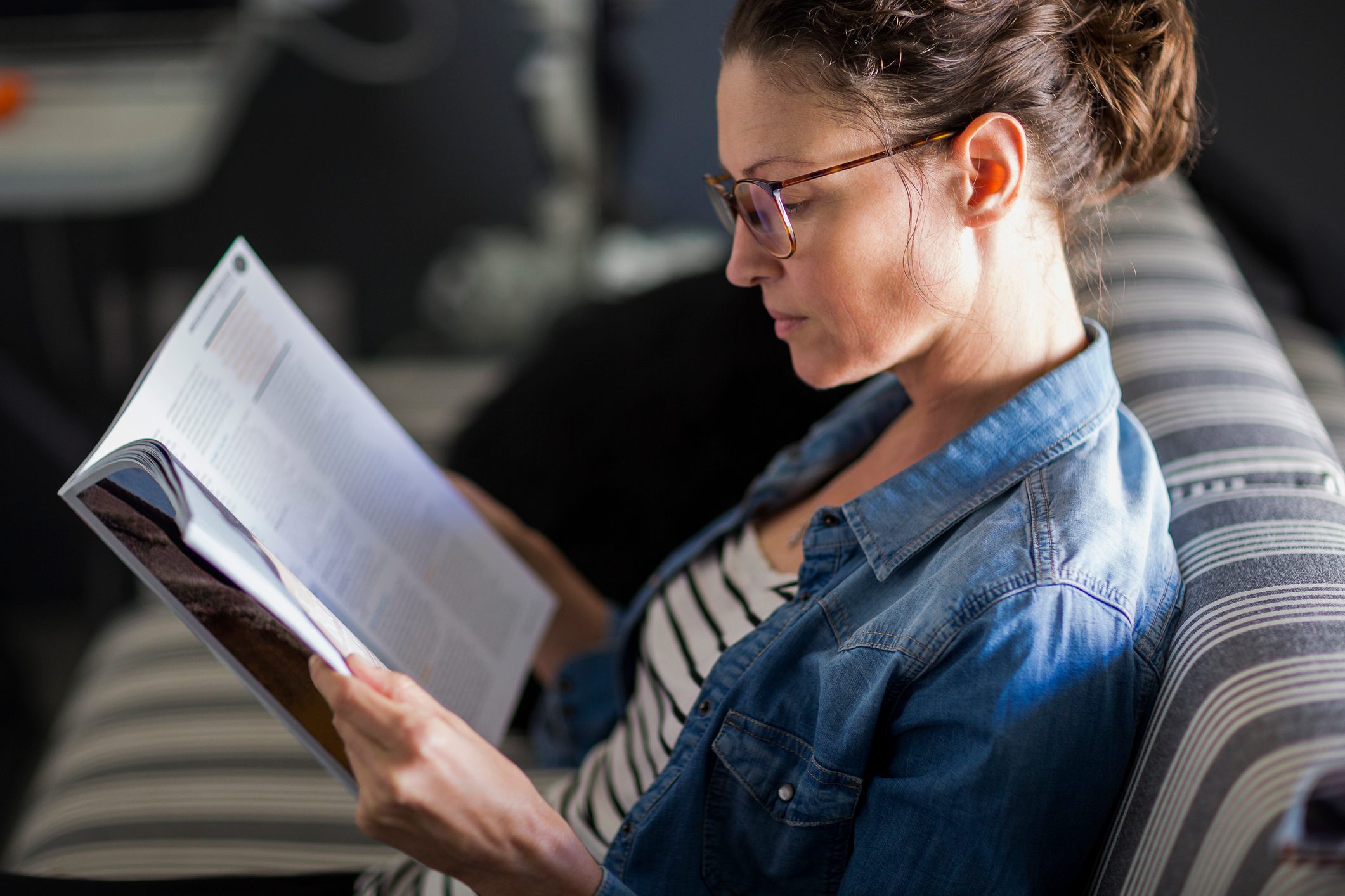 side view of woman reading a magazine at home