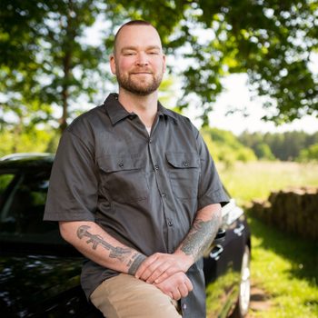 Uber driver Timothy Letts smiling and standing in front of his car