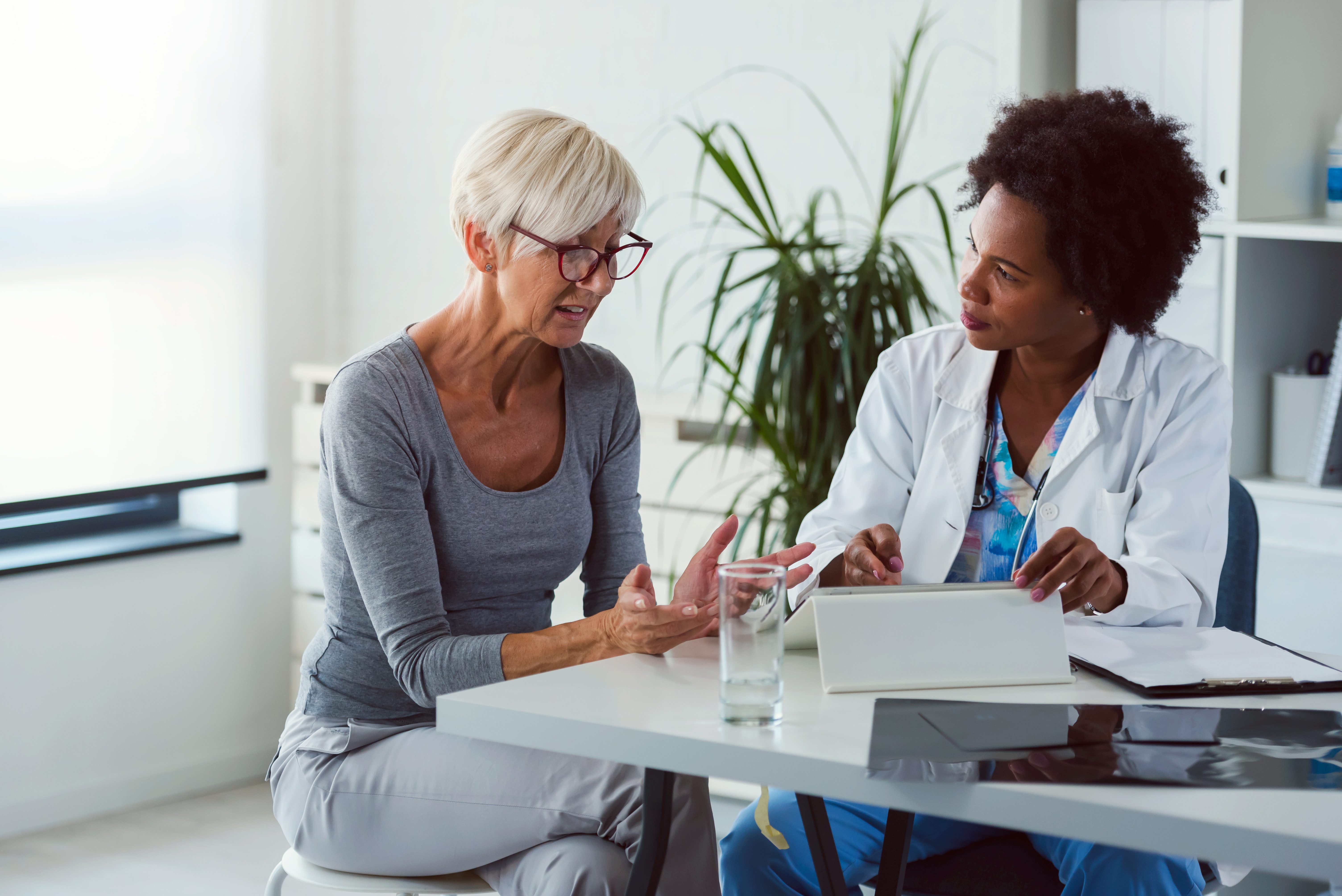 A,female,doctor,sits,at,her,desk,and,chats,to