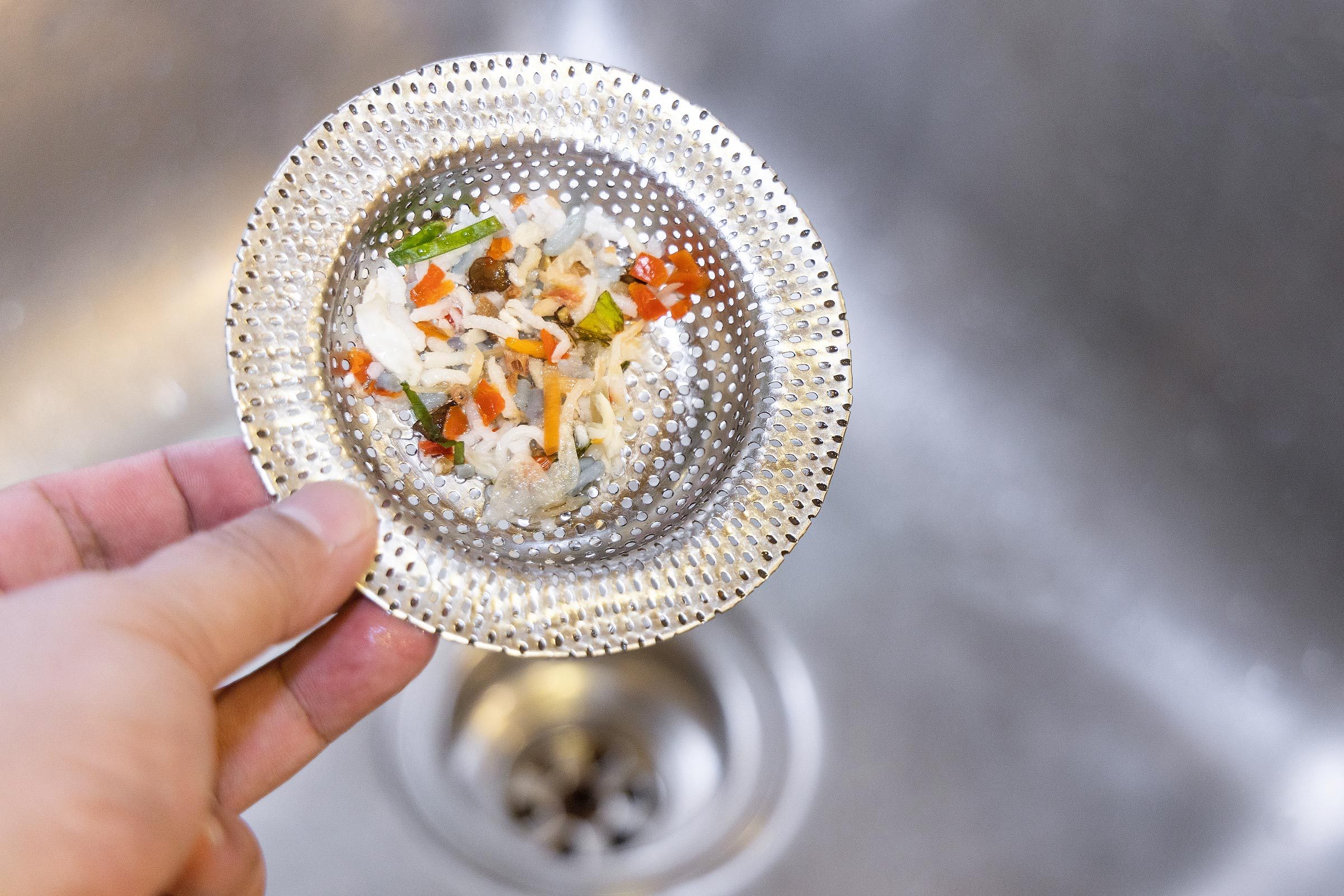 food in drain screen being removed from kitchen sink
