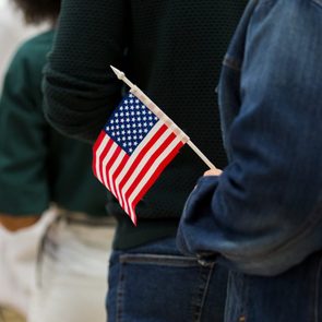 Diverse group in line to vote; one holds American flag