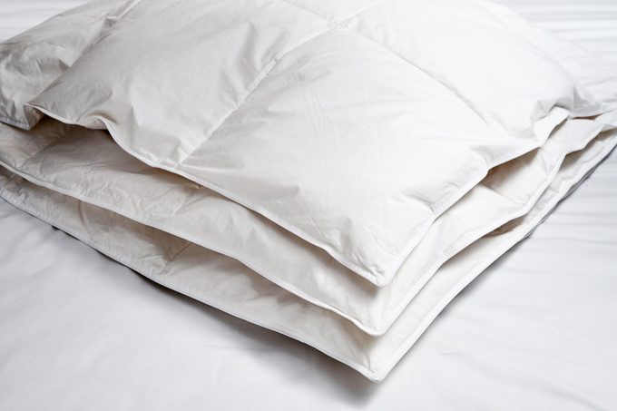 white down comforter folded on a bed