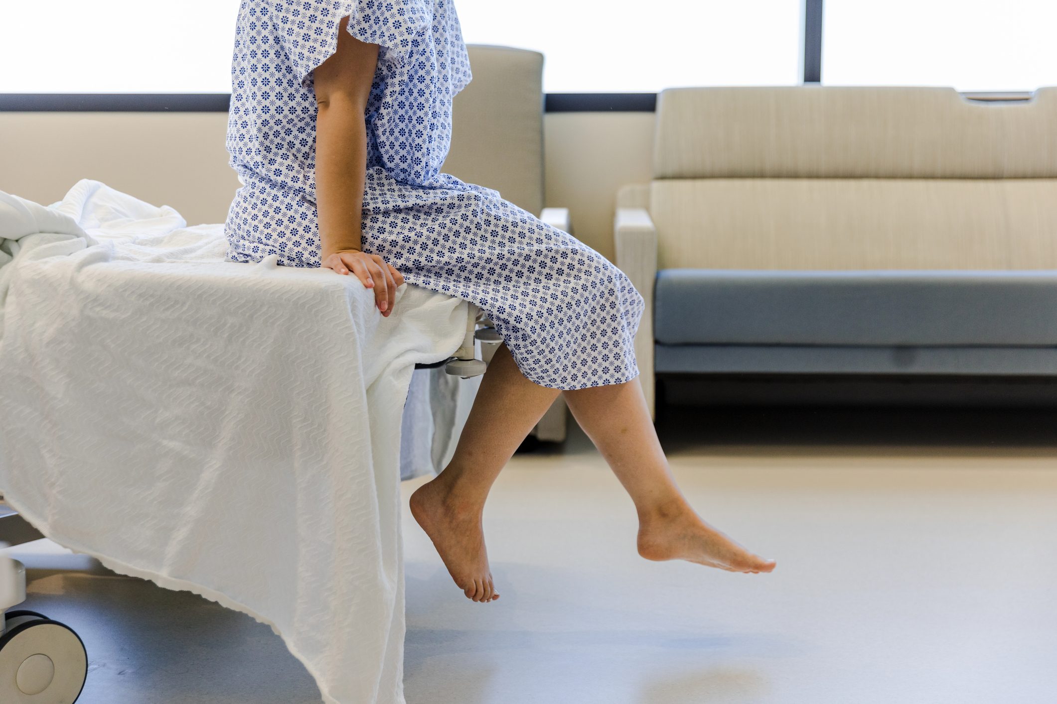 Unrecognizable female patient in hospital gown waits for test results